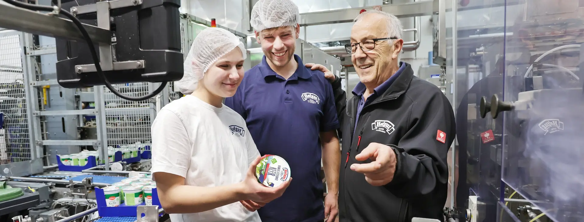 Ausbildung in der Hohenloher Molkerei. Ein erfahrener Mitarbeiter gibt sein Wissen an zwei Auszubildende weiter.