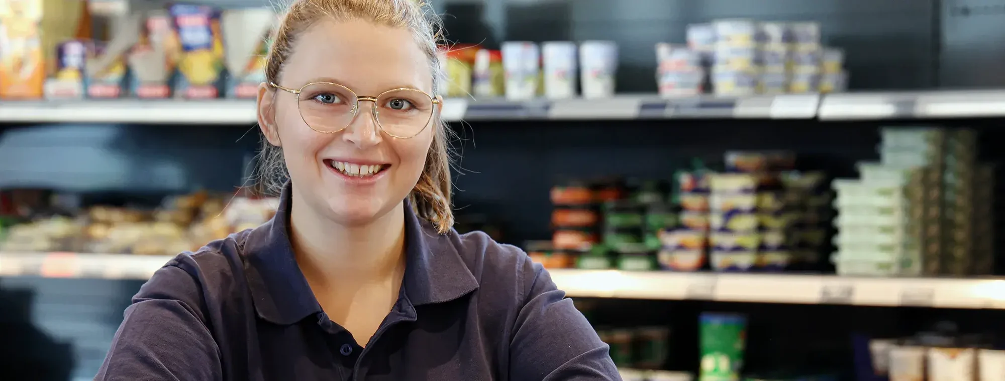 Portrait einer Mitarbeiterin vor dem Kühlregal im Hofgut-Markt