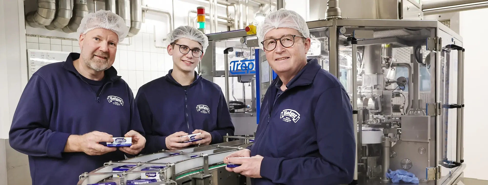 Mitarbeiter der Molkerei mit Markenbutter