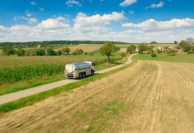 Eine Luftaufnahme von einem Milchsammelwagen der Hohenloher Molkerei auf einer Straße zwischen Feldern
