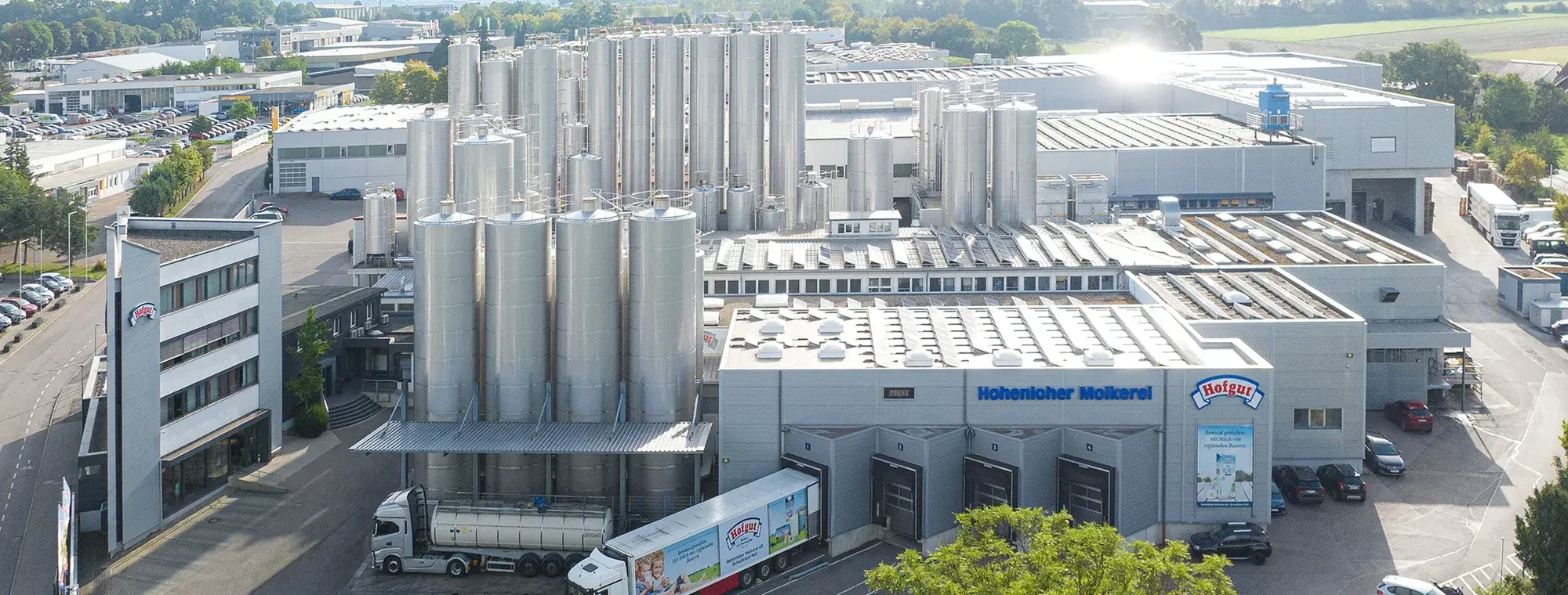Eine Luftaufnahme vom Gelände der Hohenloher Molkerei, auf der links das Bürogebäude und rechts daneben die Milchtanks sowie die Produktions- und Lagerhallen sind.
