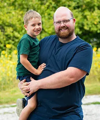Landwirt Herr Biermann mit seinem Sohn auf dem Arm
