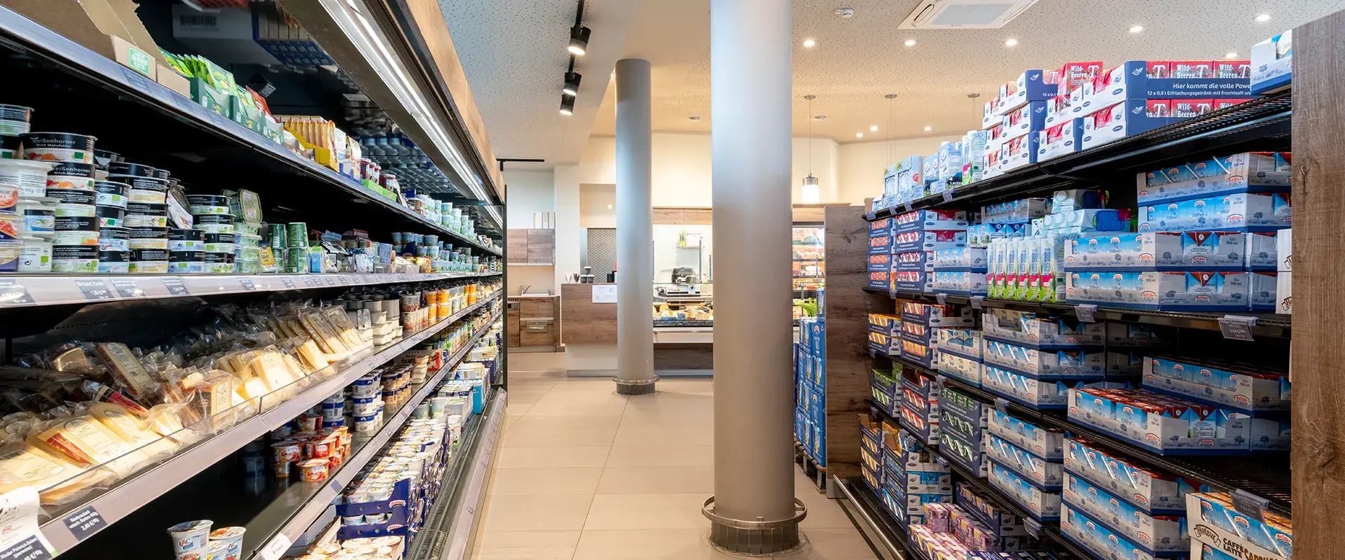 Ein Gang im Hofgut-Markt in dem links eine Kühltheke und rechts ein Regal mit verschiedenen Produkten steht