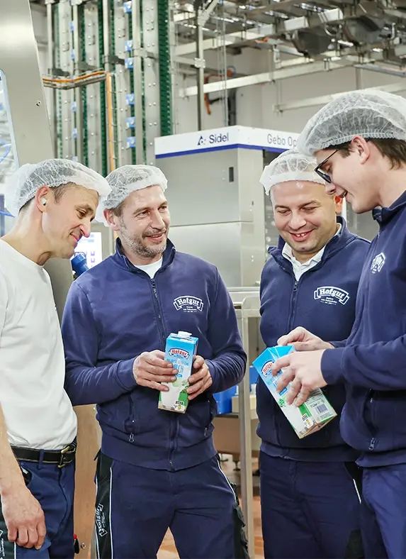 Vier Mitarbeiter der Hohenloher Molkerei stehen gemeinsam in der Produktion und unterhalten sich