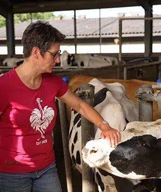 Landwirtin Frau Lutz steht im Kuhstall der Familie und streichelt eine Kuh