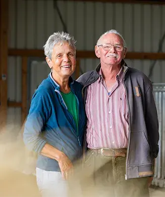 Portrait von Herr und Frau Riha Senior, die Arm in Arm lachend im Stall stehen